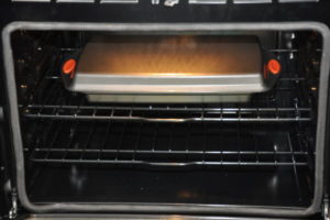 oven with bread rolls covered with a tray for rising.