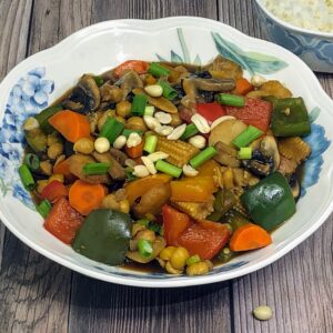chickpea vegetable kung pao in a bowl served with rice in background