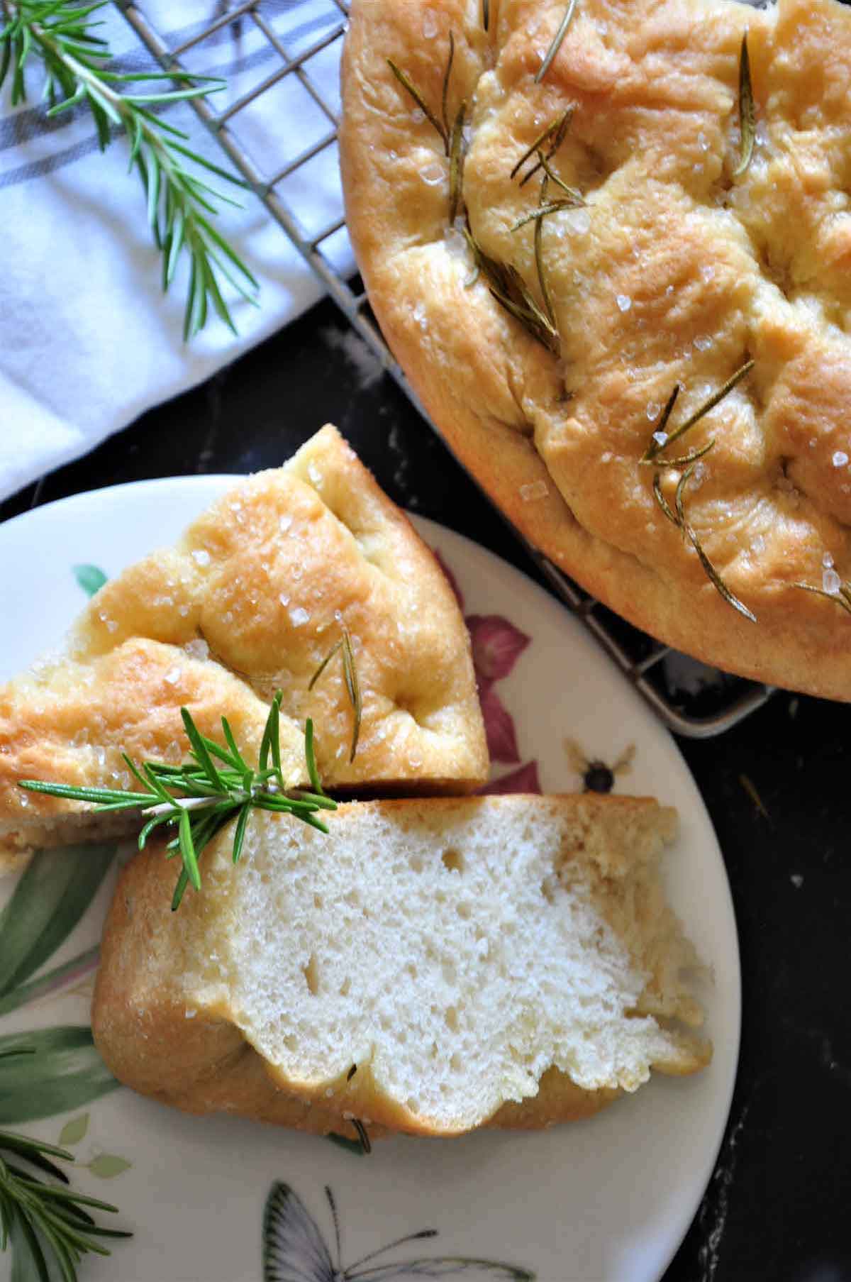 two triangles of focaccia bread with the remaining bread in background.