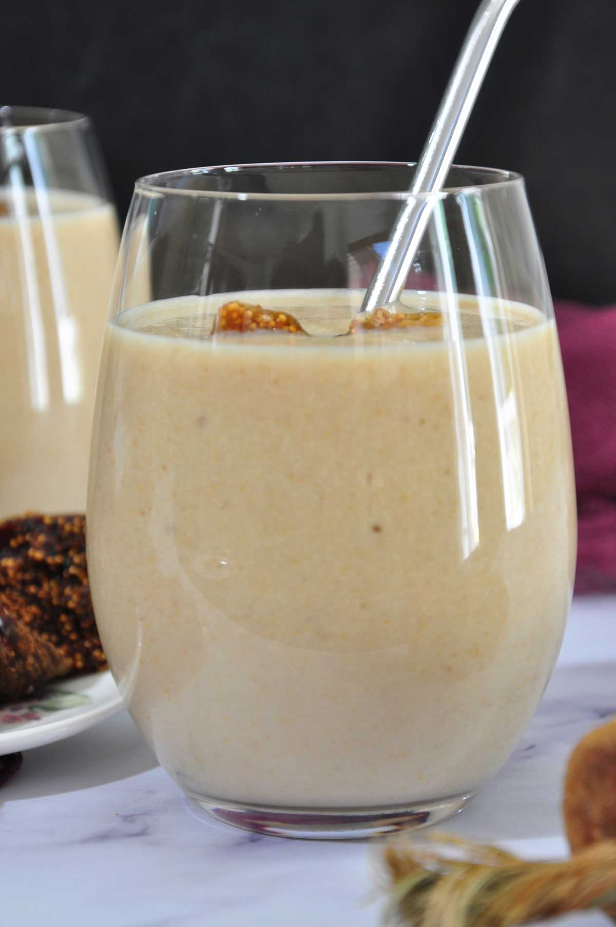 Fig smoothie in a glass with a steel straw and.