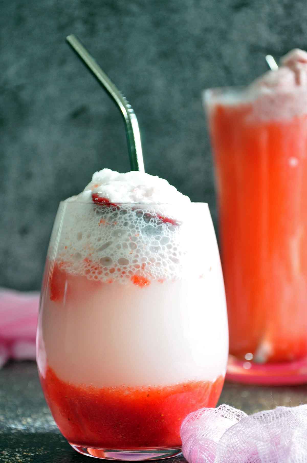 Strawberry Float in a stemless wine glass with steel straw and another float glass in the background.