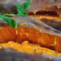 Boiled sweet potato split in the middle and coriander leaf as garnish.