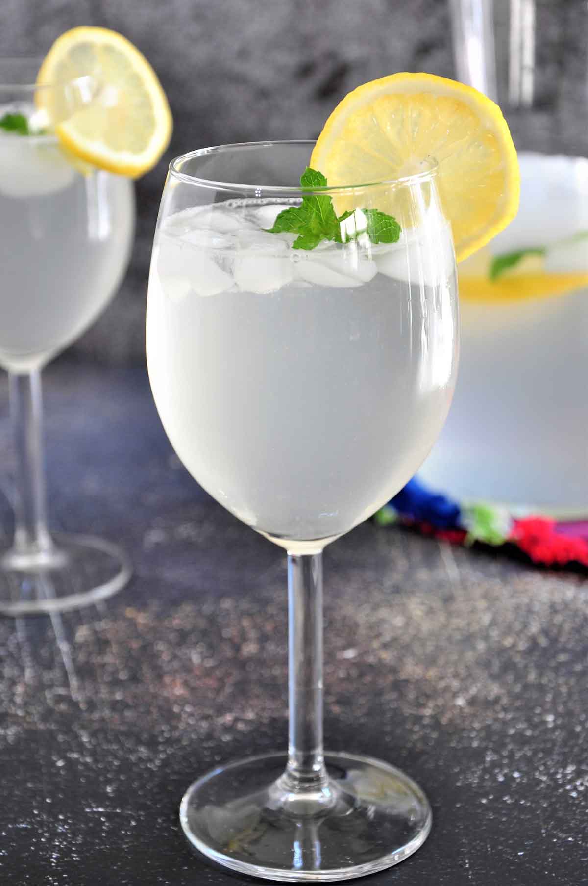 Lemonade in a wine glass garnished with lemon slice.