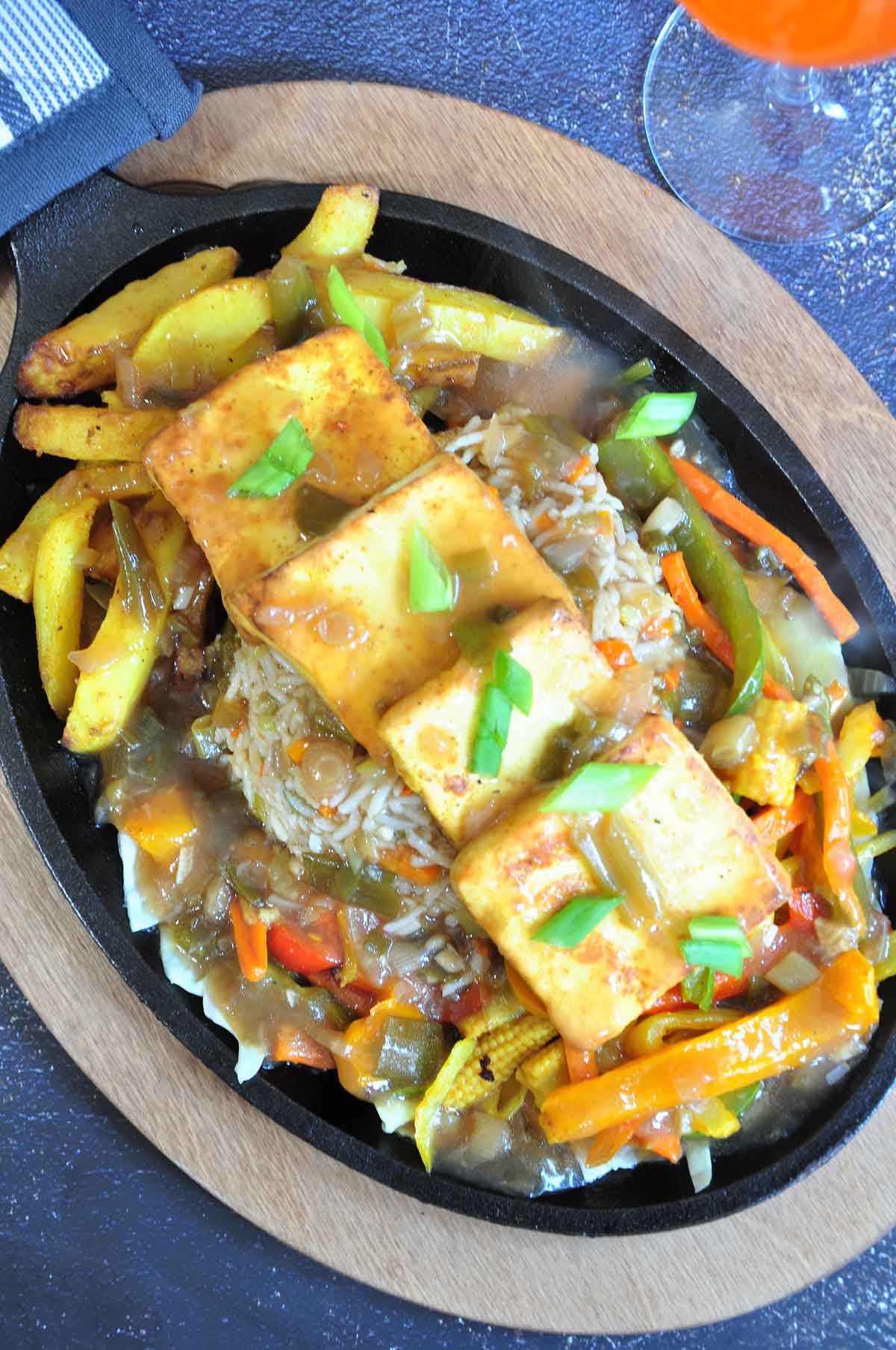 Veg paneer sizzler served on a iron sizzler plate.