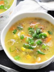 Sweet corn soup in a bowl garnished with spring onion.