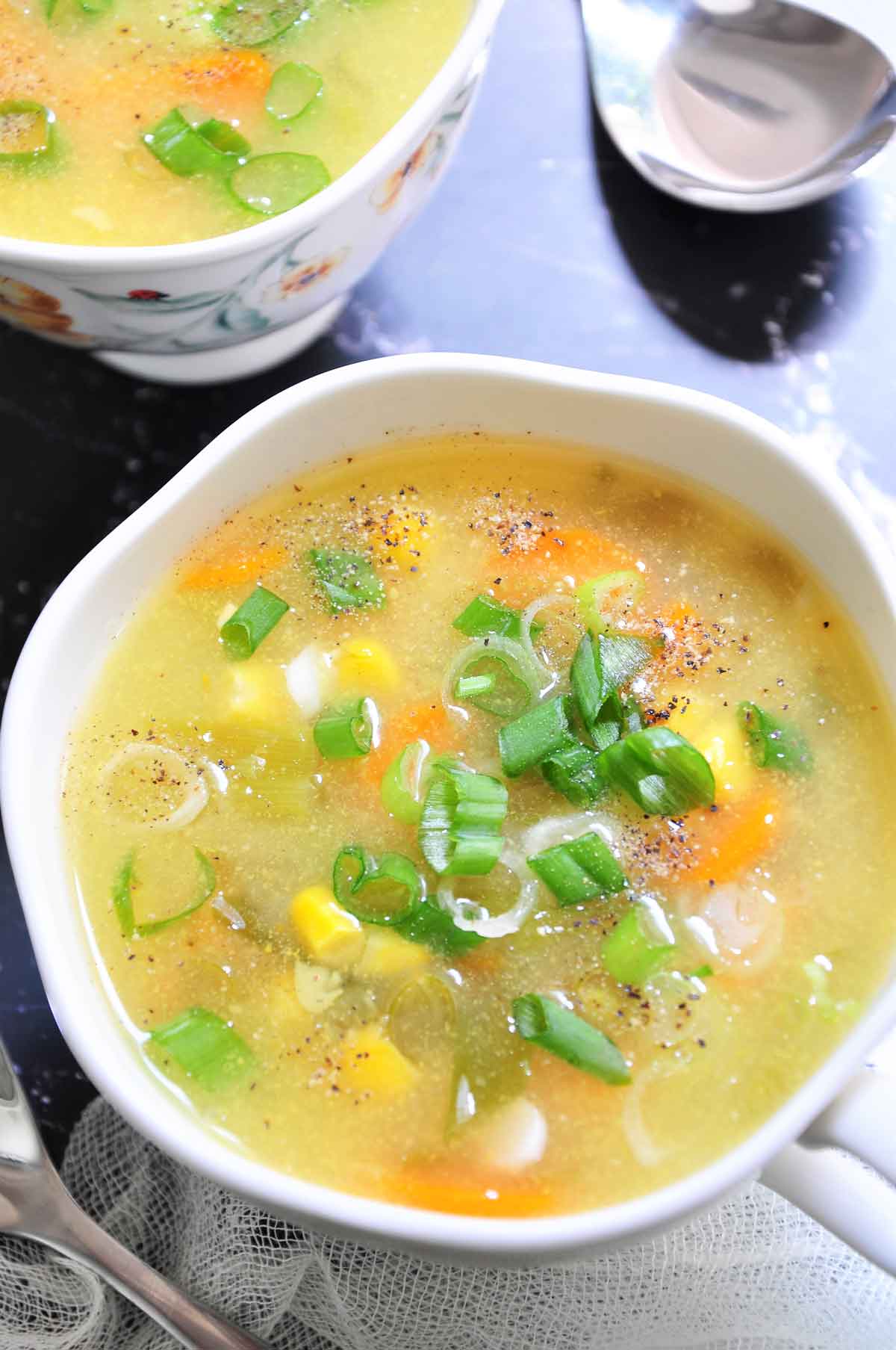 Sweet corn soup in a bowl garnished with spring onion.