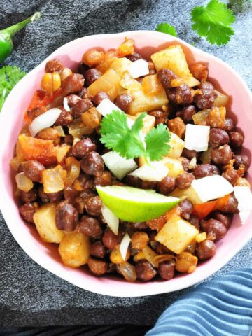 Black chickpeas (kala Chana) Chat served in a shallow bowl and garnished with slide lime.