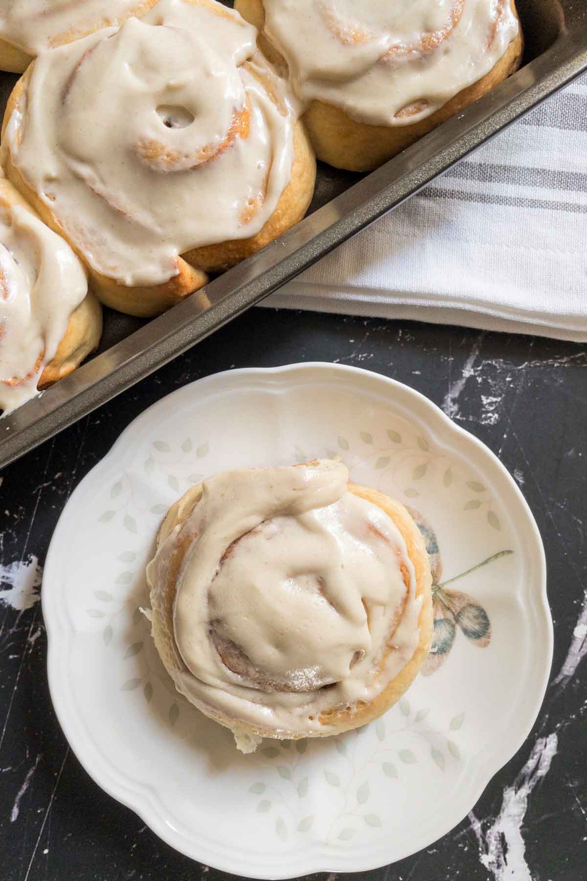 a cinnamon roll in a plate with icing on top.
