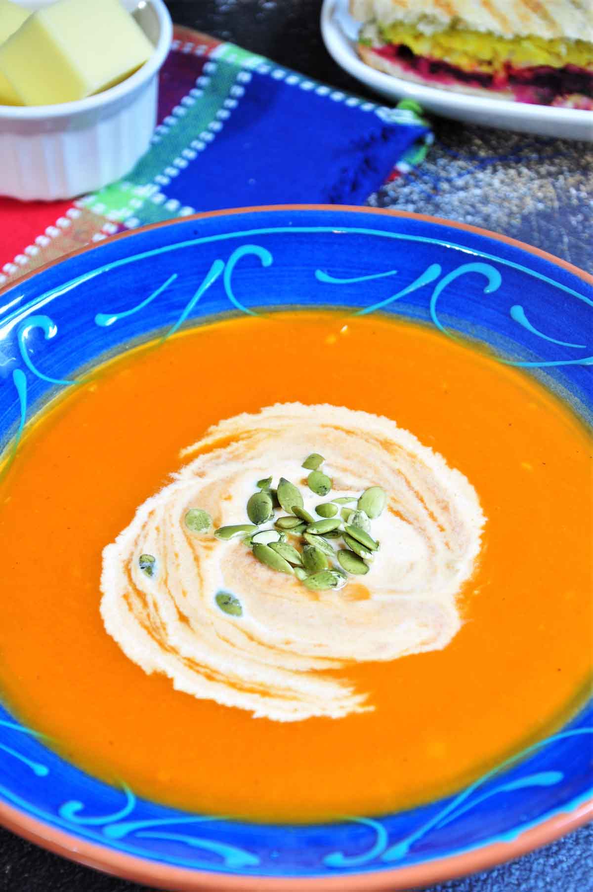 Carrot soup in a soup bowl, garnished with cream and pumpkin seeds.