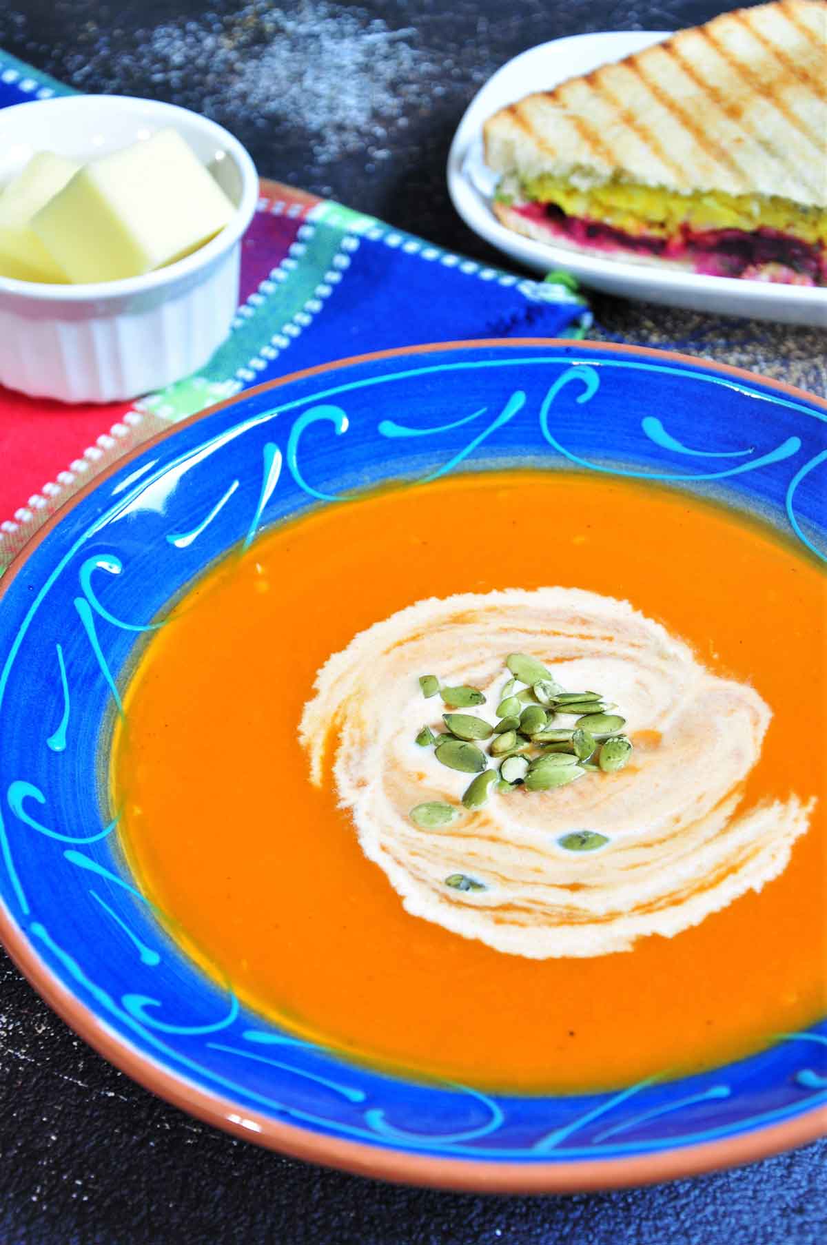 Carrot soup in a soup bowl, garnished with cream and pumpkin seeds.