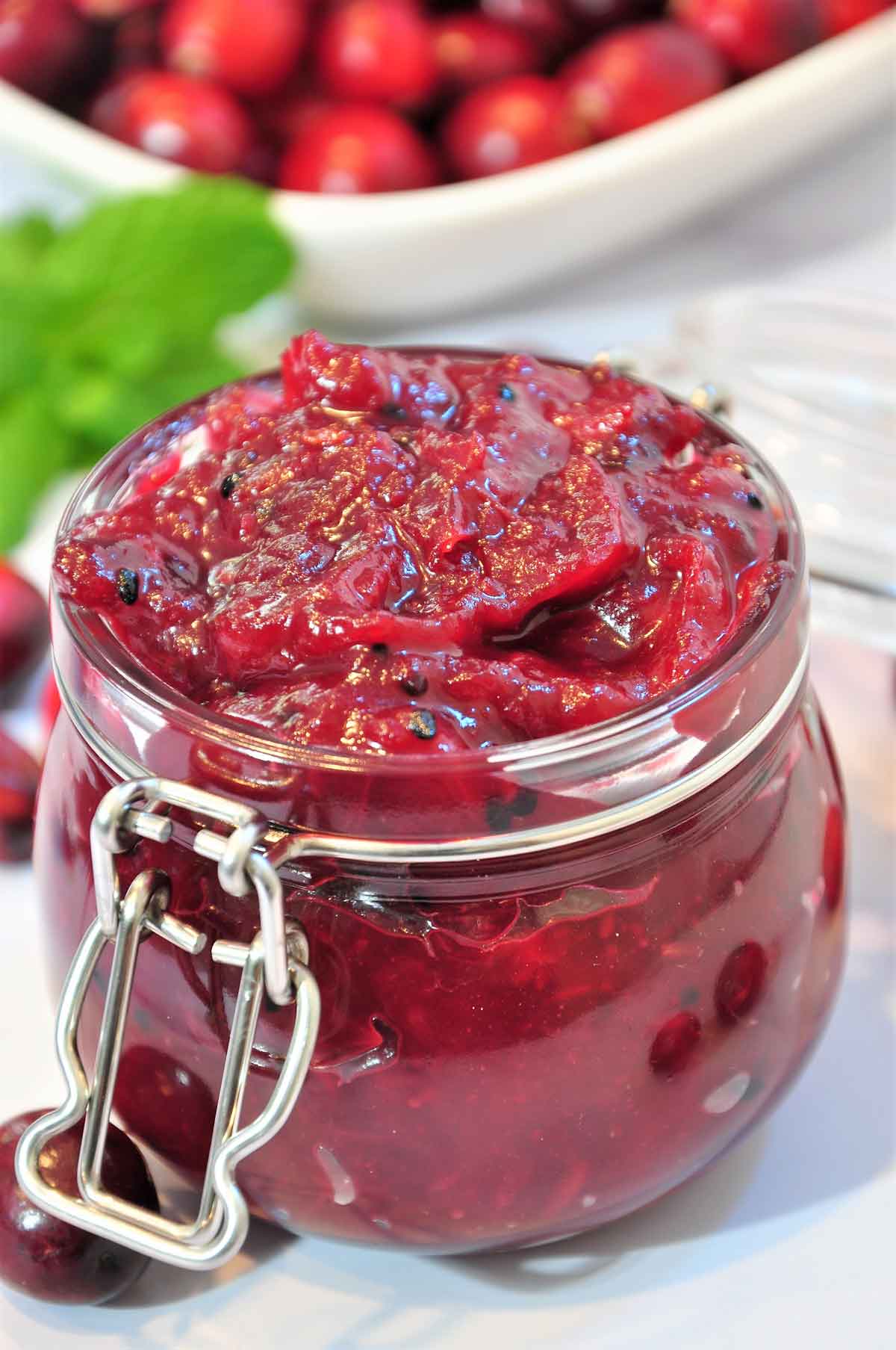 fresh craneberries along with craneberry chutney in a jar