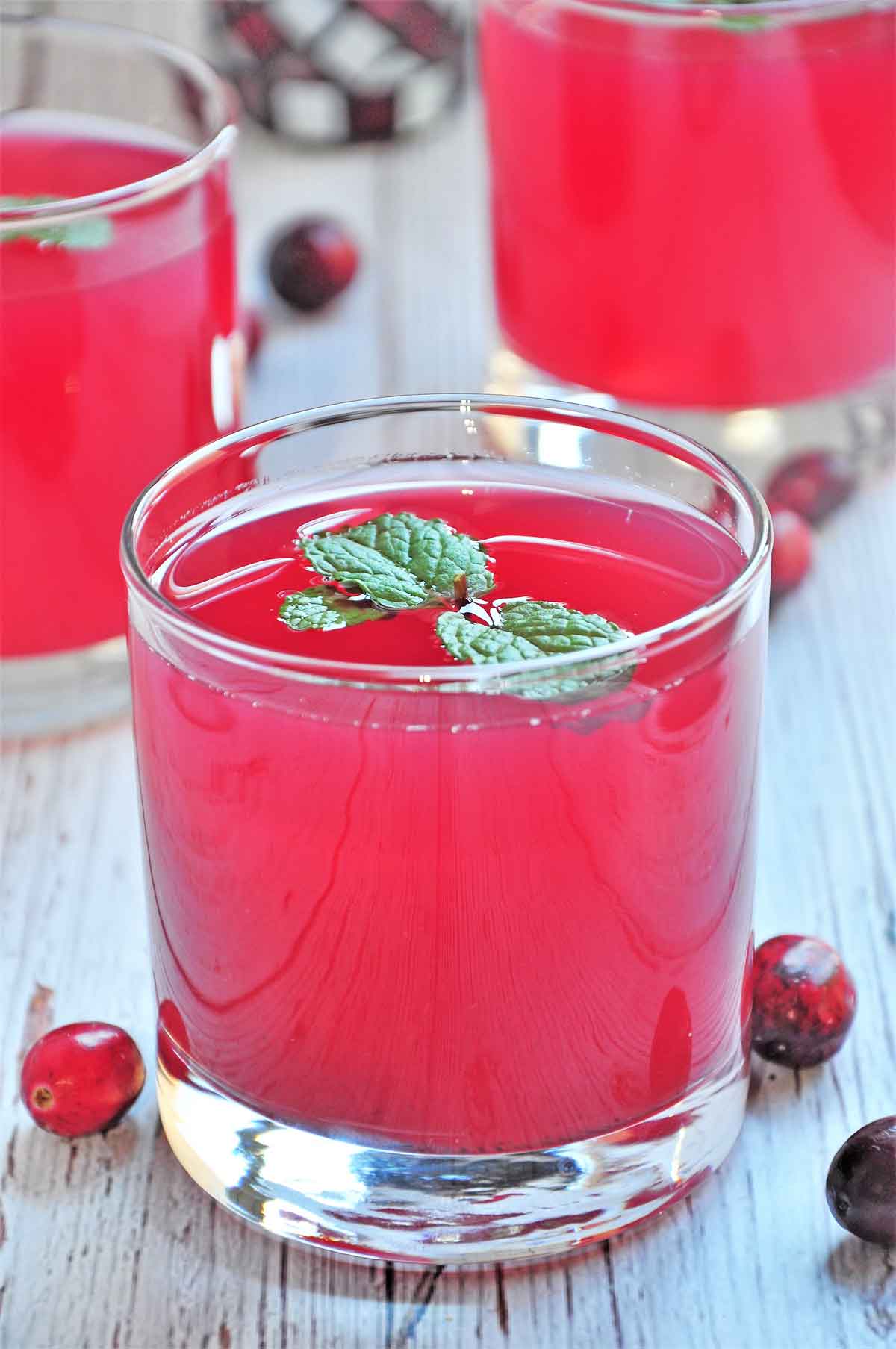 Cranberry juice in a glass and garnished with few mint leaves.