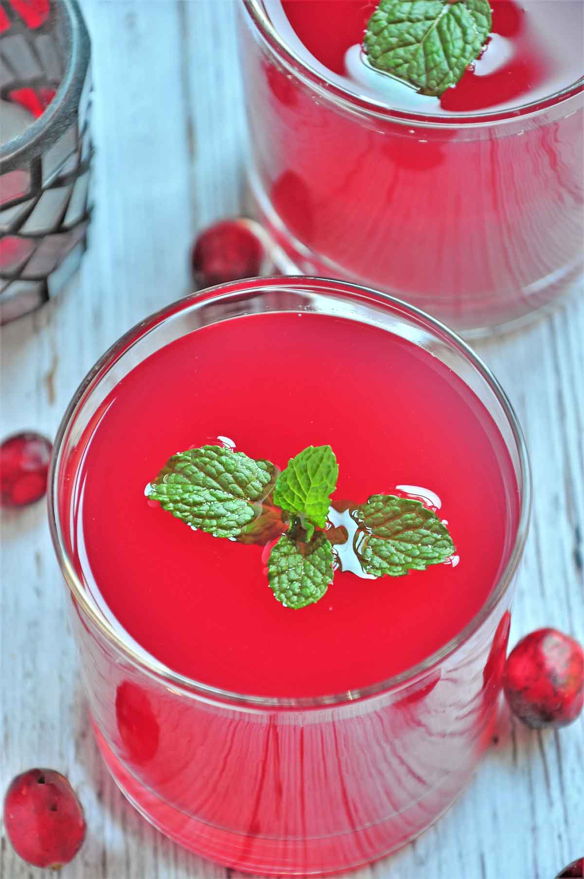 Cranberry juice in a glass and garnished with few mint leaves.