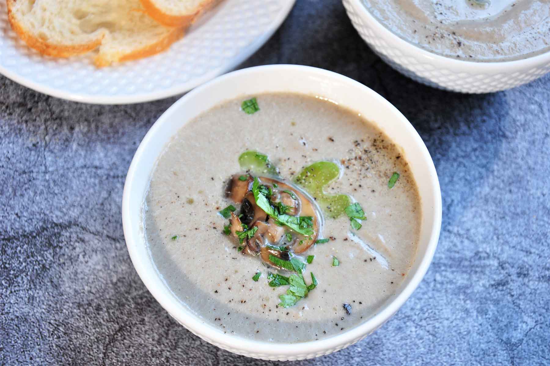 Cream of mushroom soup in a bowl garnished with cooked sliced mushroom and cilantro.