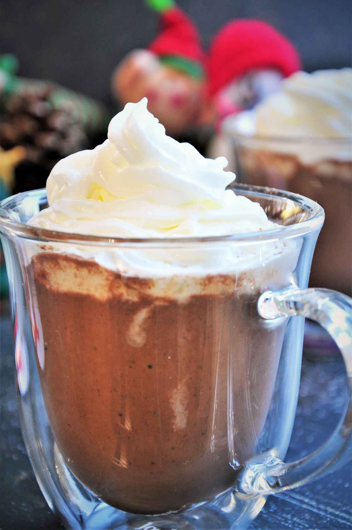 Hot cocoa in a cup topped with whipped cream.