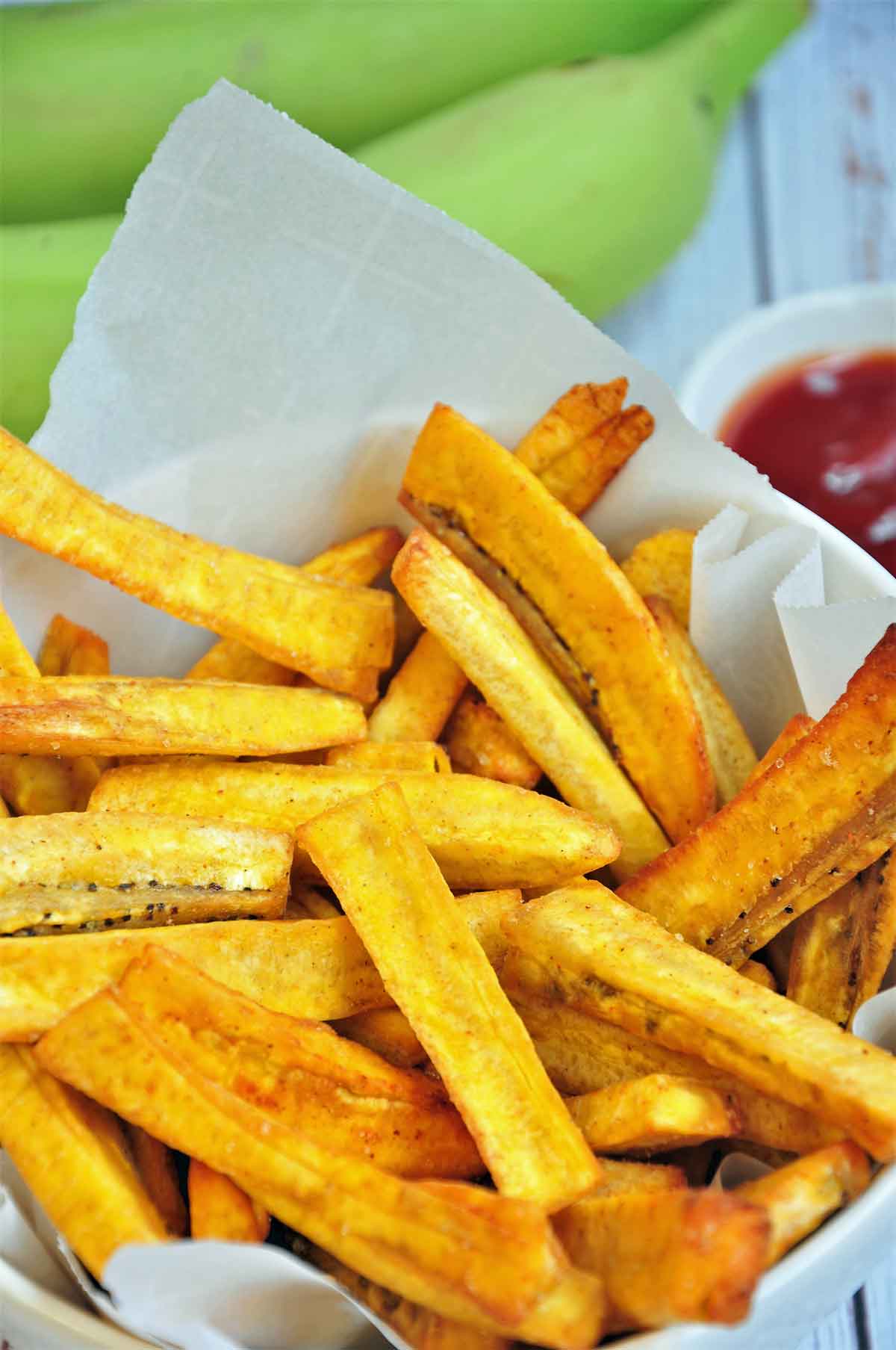 Plantain fries served in a bowl with ketchup on the side.