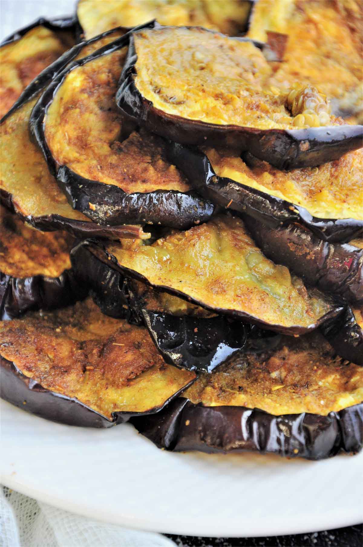 Roasted eggplant slices stacked in a serving plate.