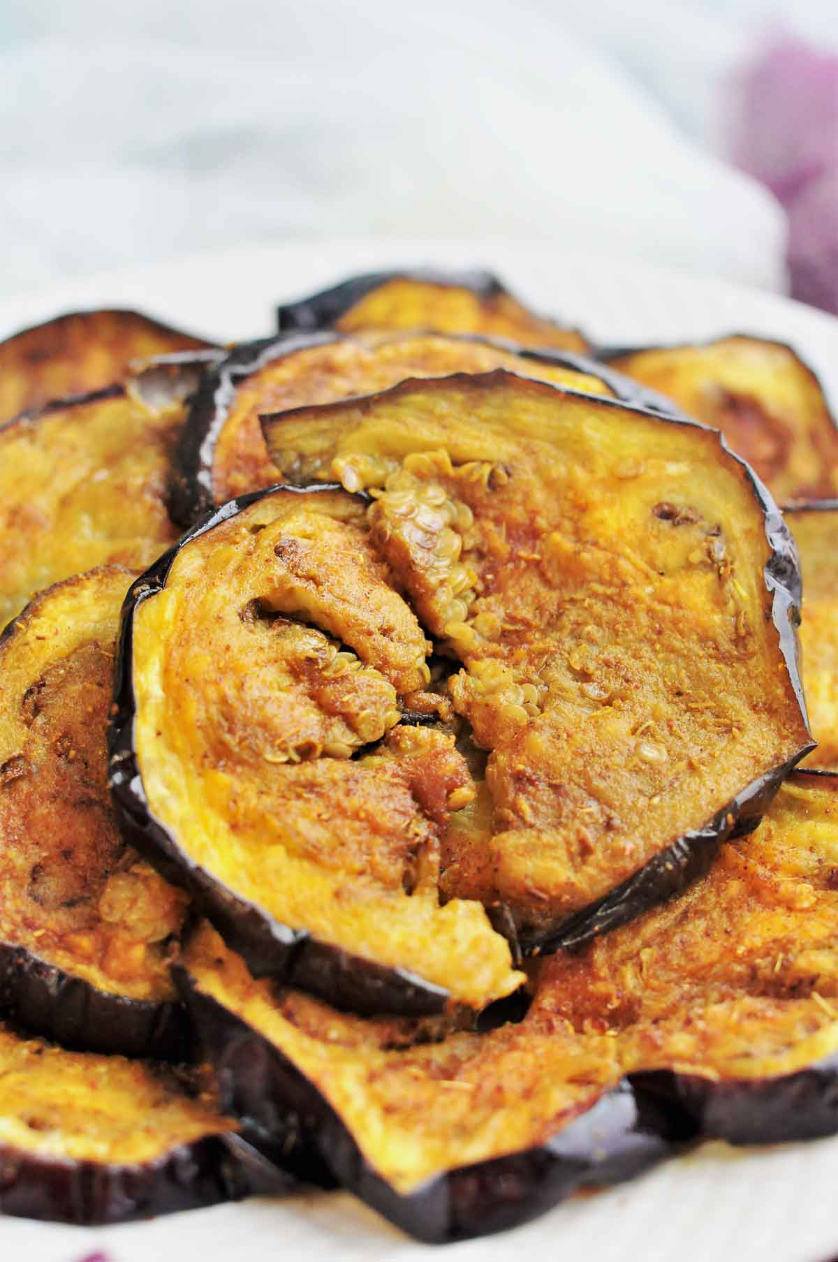 Roasted eggplant slices stacked in a serving plate.