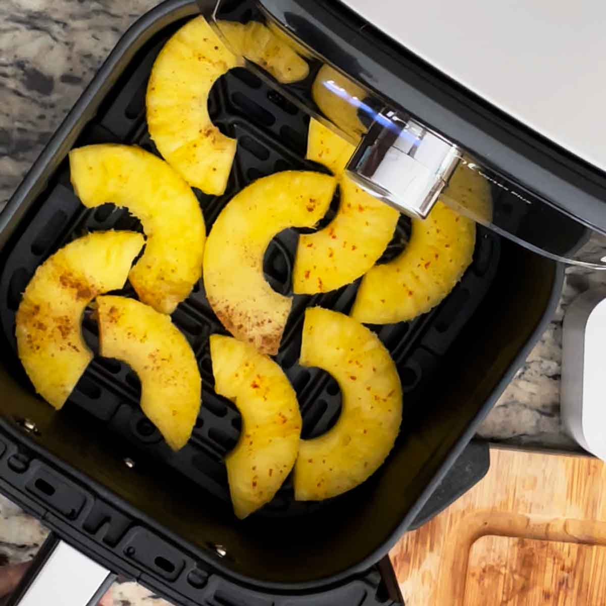Sliced pineapple chunks placed in air fryer.