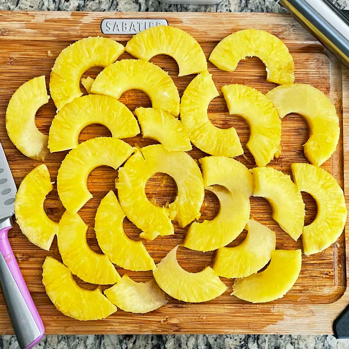 Sliced pineapple chunks on a cutting board.