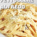 Fettuccine Alfredo served in a plate with shredded cheese topping.