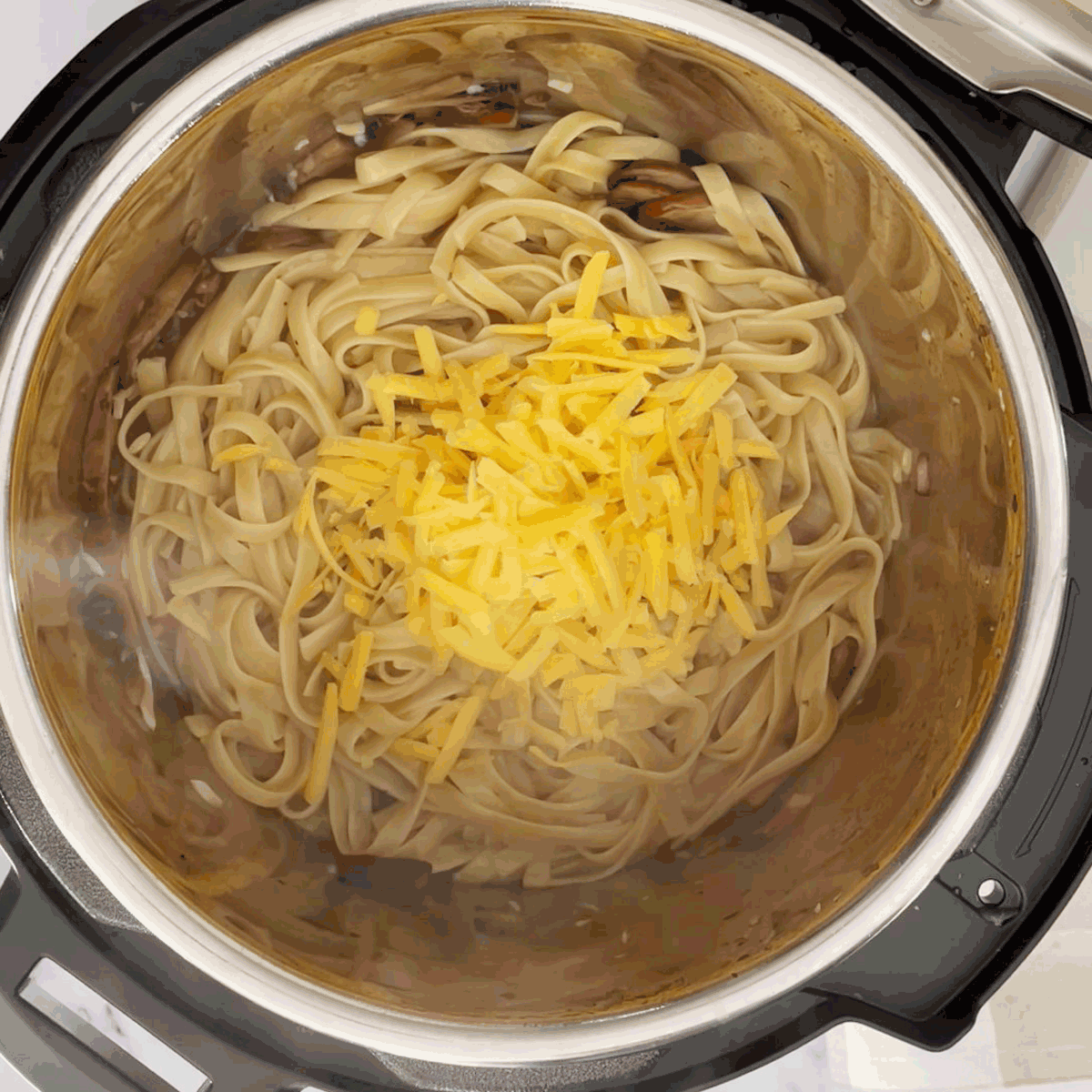 Add cheddar cheese to boiled pasta.