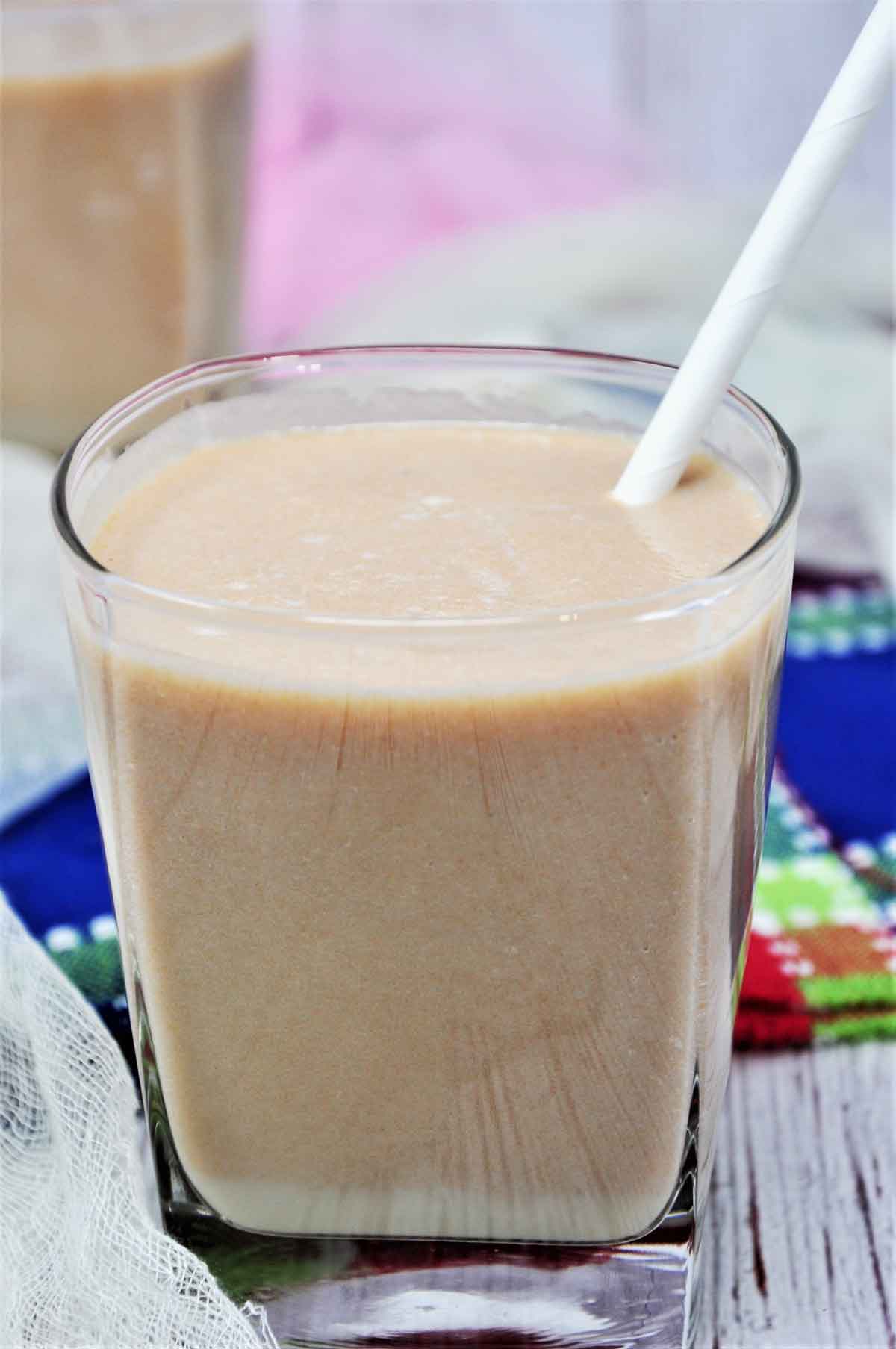 Chikoo milkshake served in a glass with straw,