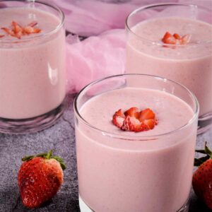 Strawberry milkshake served in a glass and topped with strawberry.