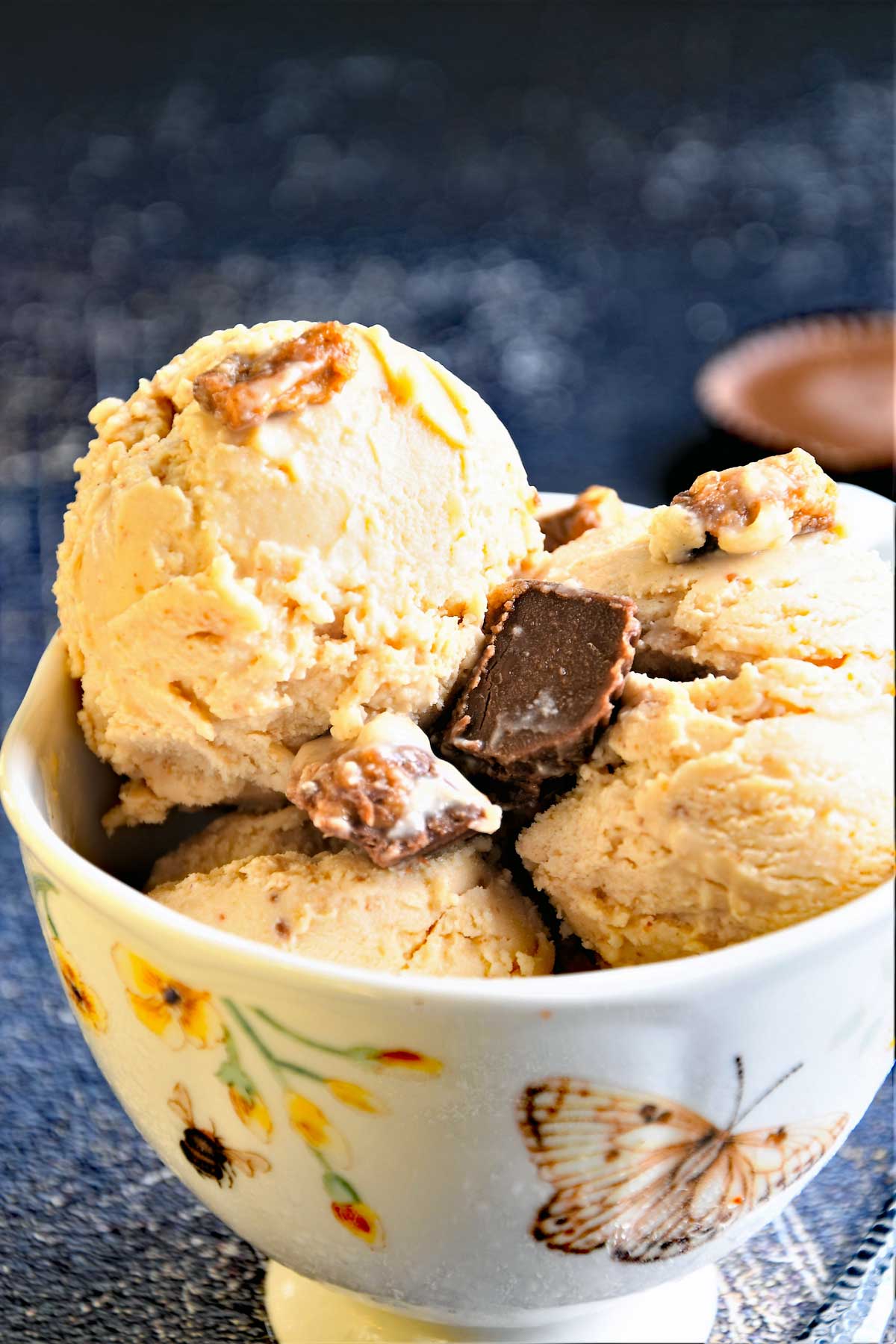 Peanut butter ice cream scoops served in a bowl with Reese's topping