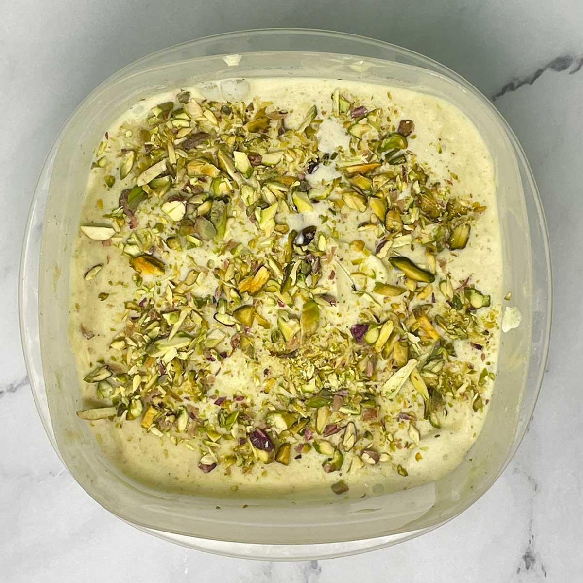 Pistachio ice cream ready to freeze in a container.