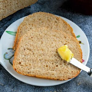 Multi-grain bread slices with a little butter scoop on a cheese board.