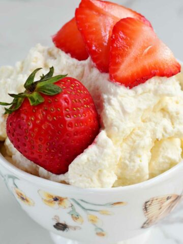 Whipped cream in a cup with strawberries.