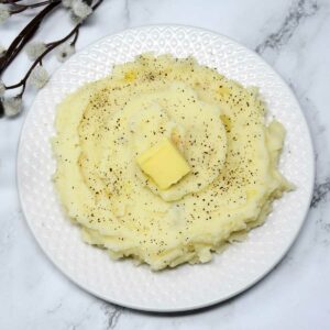 Mashed potato in a plate with butter cube as topping.
