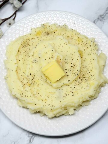 Mashed potato in a plate with butter cube as topping.