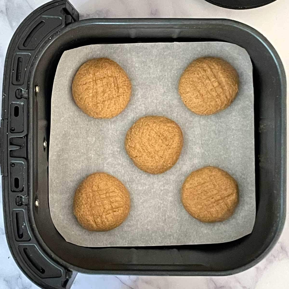 Peanut butter cookies in air fryer tub.