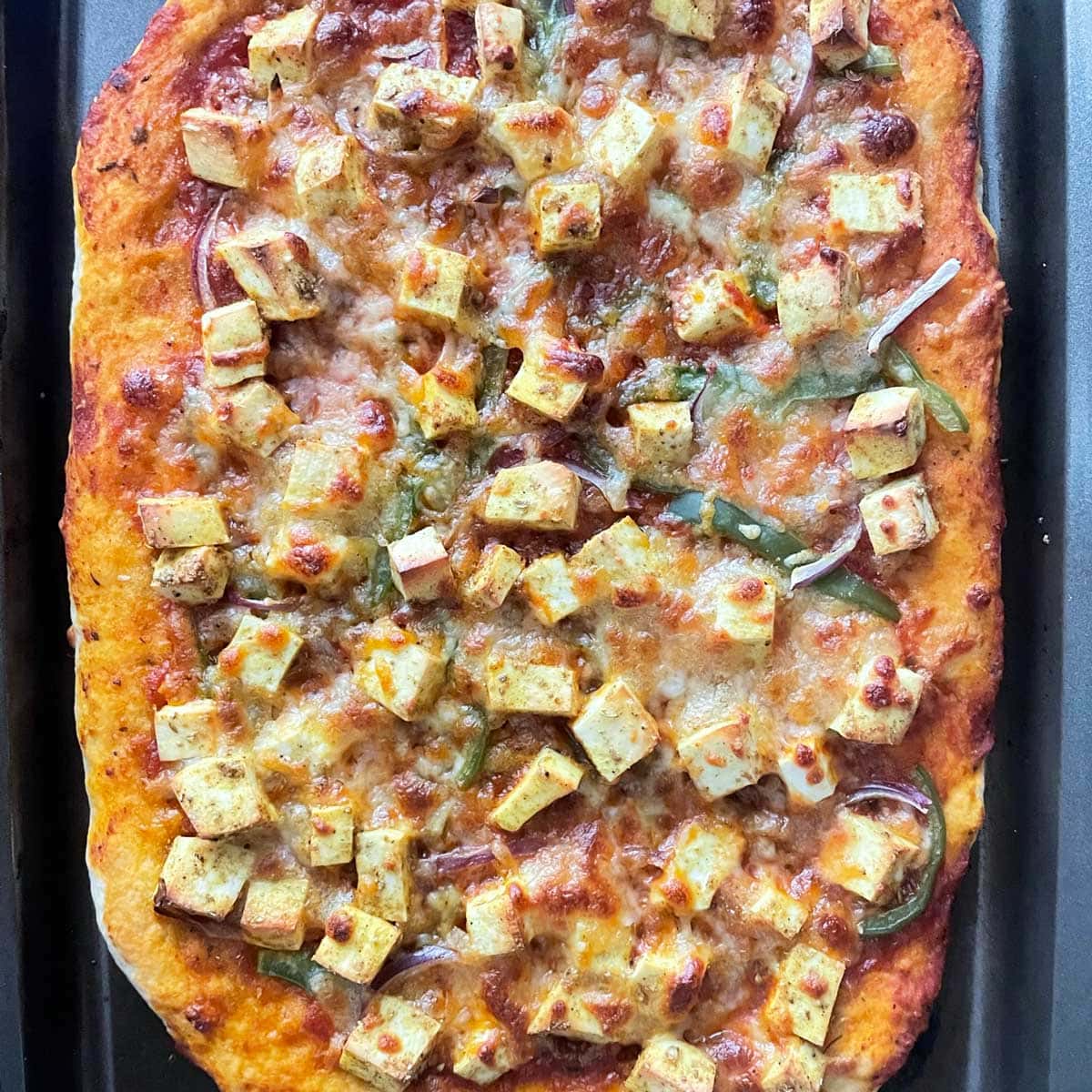 Paneer pizza in baking tray.