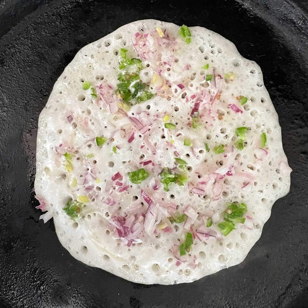 Garnish with onion and green pepper over uthappam batter.