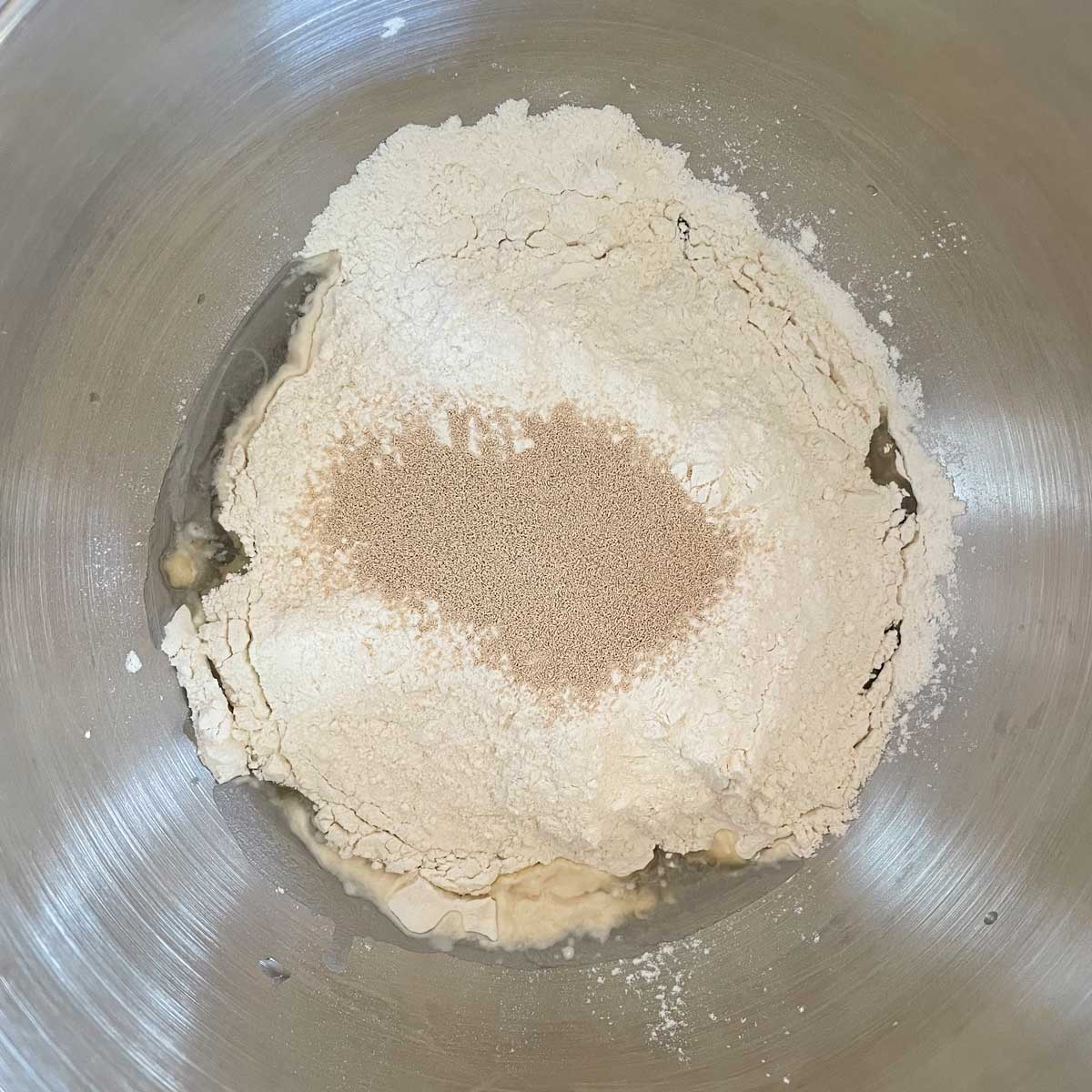 Pizza dough ingredients in a stand mixer bowl.