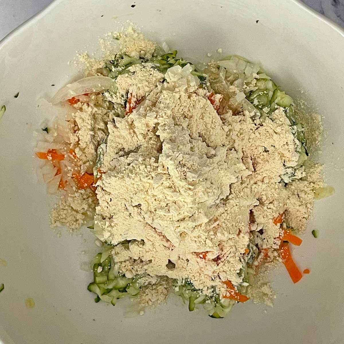 Shredded Zucchini and other ingredients in a bowl.