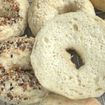 A bunch of bagels on a cooling rack.