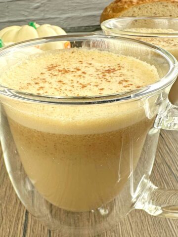 Pumpkin spice latte in couple of clear coffee mugs.